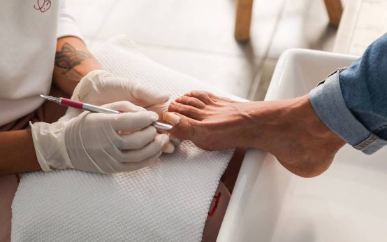 Imagen de profesional de cuidado de los pies con un cliente en el momento de trabajo